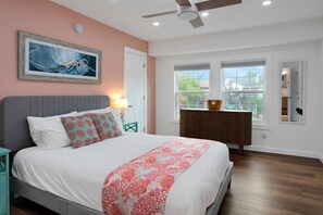 The primary bedroom features a queen bed, a workspace, a TV, and an ensuite bathroom.