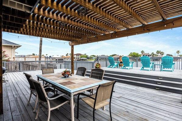 Shaded outdoor dining area with plenty of seating for the family that overlooks the water