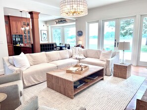 Open concept kitchen living dining area overlooking water and outdoor deck 