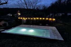 Outdoor private heated pool with lights at night
