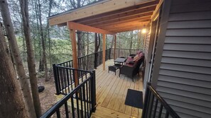 Porch surrounded by pine and cedar trees.
