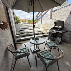 Private terrace for guests with grill, three seating places and a small table.