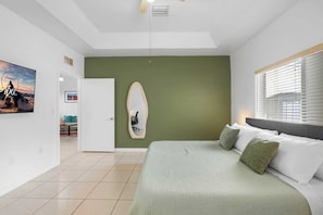 The master bedroom features a king-sized bed, a smart TV, a full-length mirror, nightstands, and a small work desk. It also includes an en-suite bathroom for added convenience.