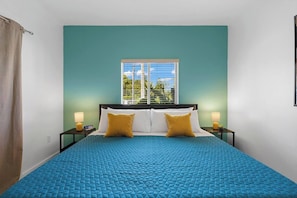 This cozy bedroom features a king-sized bed, nightstands, lamps, and alarm clocks.
