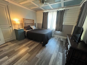 Full size bed along with couch and ottoman in room with TV.