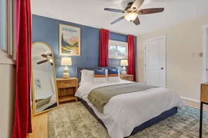 Bedroom with plush beddings, standing mirror, and ceiling fan