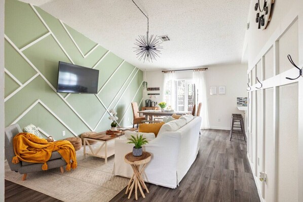 Stylish open living area with chic accent wall, cozy seating, and ample natural light.