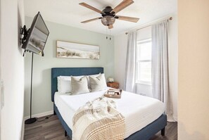 Cozy bedroom with stylish decor, comfy bed, and a wall-mounted TV for relaxation.
