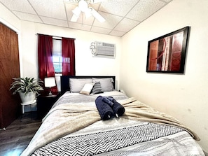 Bedroom with Queen size bed, AC, ceiling fan, amd darkening shades.