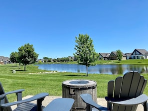 Adirondack chairs next to fire pit facing the pond