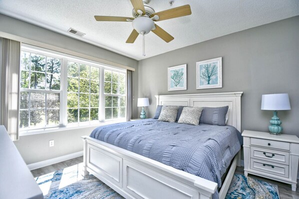 This bedroom offers a serene retreat with a plush king-sized bed and abundant natural light streaming through large windows.