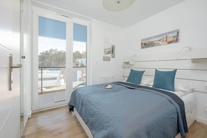 A bedroom with a large bed, blue bedding, and window, offering plenty of natural light.