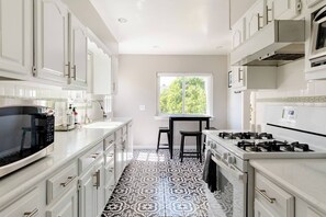 The galley style kitchen is filled with natural light and a lovely view of the backyard.  There is a stove, oven, microwave, dishwasher and eat-in table that seats four (4).