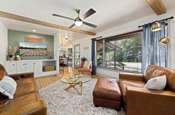 Cozy living room with warm leather seating, a large picture window with scenic views, and stylish decor featuring natural wood accents.