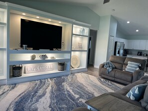 Cozy Great Room with 75" TV, reclining couches, ceiling fan, mood lighting.