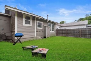 Backyard with grill and cornhole set.