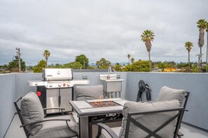 Front house rooftop deck with fire table, gas BBQ and ice chest cooler.