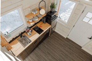 Tiny cabin kitchenette has all the supplies for cooking and dining.