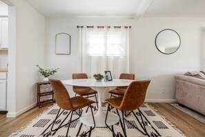 This contemporary living area, featuring a white marble table, brown chairs, and decorative mirrors, fosters a welcoming ambiance with minimalist flair.