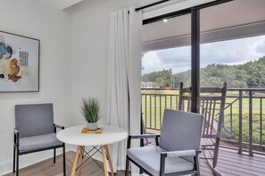 A room with inviting seats and a table, where the balcony beckons with the promise of fresh air and scenic views. An indoor comfort that we need.