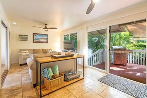 A spacious living room, bathed in natural light, invites a seamless connection to the lush balcony greenery.