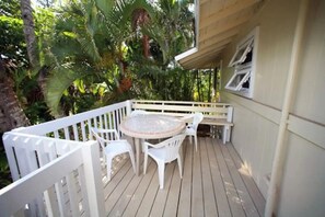 An outdoor oasis with a round mosaic table and white plastic chairs on a wooden deck perfect for alfresco treat.