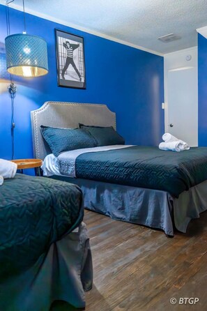 Indulge in the serenity of our blue suede-themed space, featuring two double beds, a TV, and a functional work desk.