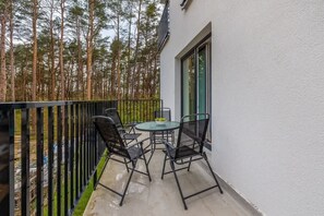 A balcony with a view of surrounding greenery. The balcony is furnished with a small table and chairs, perfect for relaxing outdoors.