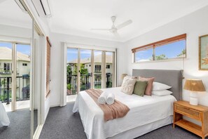 Retreat to the primary bedroom, featuring a comfortable queen bed, air conditioning, and sliding doors that open to a private balcony. 