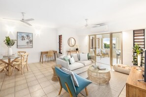 Relax in the airy living area, featuring a cosy linen lounge and central TV. 