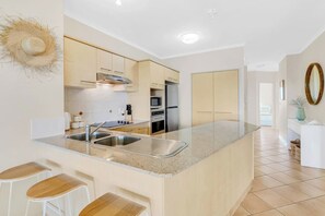 A fully-equipped kitchen has breakfast bar seating and premium appliances including an oven, a Nespresso machine, and a dishwasher