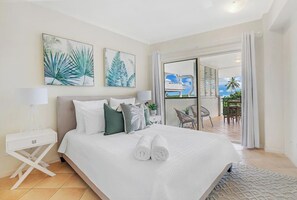 A bright and breezy first bedroom has a queen bed, an ensuite bathroom and direct access to the balcony.
