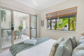 The primary bedroom features a comfortable queen bed, built-in robes, an ensuite bathroom, and access to the balcony.