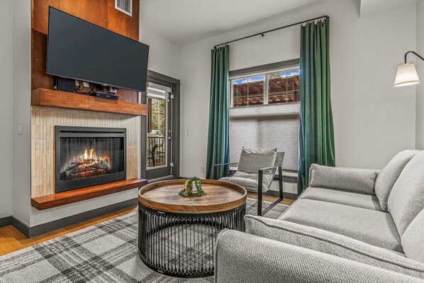 A cozy gas fireplace, big screen smart TV, and upscale designer furniture in the living room