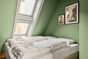 Twin bedroom with sloped ceilings and soft green accents.