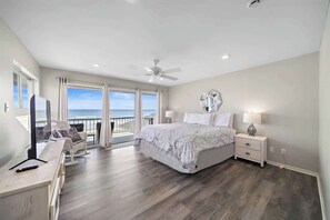 Master bedroom with a king-size bed, cozy bedding, fresh linens, and direct access to a patio with comfortable seating