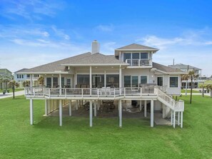 Beautiful home with a patio surrounded by a lush grassy yard and living spaces on the second floor