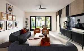 (1st Floor) Open floor plan main living area with designer decor, smart TV, comfortable seating, and access to the backyard.