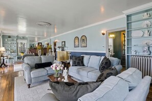 Living Room (Unit 1) -Step inside this elegantly appointed living room, featuring soft hues and vintage decor, creating a perfect blend of comfort and style for your stay in the Finger Lakes. Ideal for leisurely afternoons or cozy evenings in.