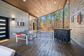 Seamless blend of recreation and relaxation with an expansive outdoor ping pong area, under a natural pine canopy.