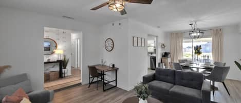 Spacious open living area with modern decor, desk workspace, and natural light.
