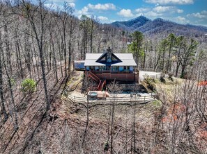Back of house with view of hot tub and fire pit