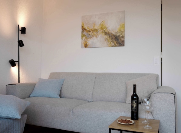 Modern lounge area with cozy touches
Relax with a glass of wine in this bright, inviting space featuring a soft sofa, elegant lighting, and serene artwork.
