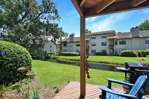 Private Patio Overlooking the Creek – Harbour Oaks 409, St. Simo - Covered patio with Adirondack chairs and gas grill—perfect for relaxed evenings beside the creek. One of the most peaceful condo settings on St. Simons Island, just a short walk to Pier Village.