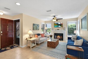 Living Room with Fireplace & Smart TV – Harbour Oaks 409 - Bright and welcoming living room with hand-built furniture, smart TV, and decorative fireplace—cozy up after a beach day in this St. Simons Island condo near Pier Village.