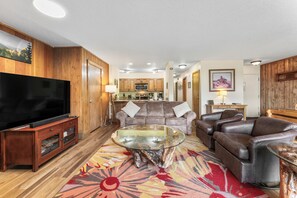 Living area with smart TV, hardwood flooring, access to the private balcony and a wood-burning fireplace.