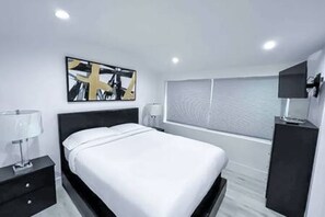 Bedroom 2 features a cozy queen-sized bed, a closet and dresser for ample storage, an en-suite bathroom, and a TV for your relaxation. A perfect retreat for comfort and convenience.