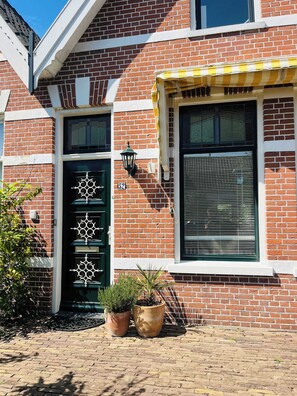 The entrance features eye-catching nautical elements and cheerful potted plants, creating a warm welcome before stepping into the stylish comfort inside.

