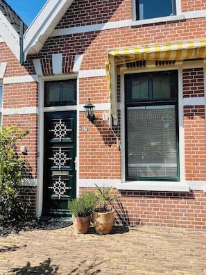 The entrance features eye-catching nautical elements and cheerful potted plants, creating a warm welcome before stepping into the stylish comfort inside.