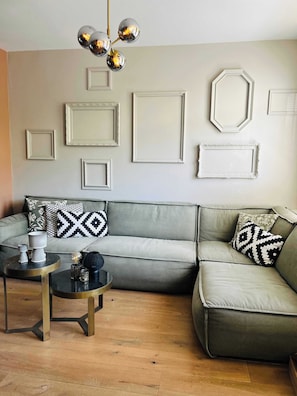 Unique and inviting sitting area featuring a soft green couch and decorative wall art made from painted empty frames.